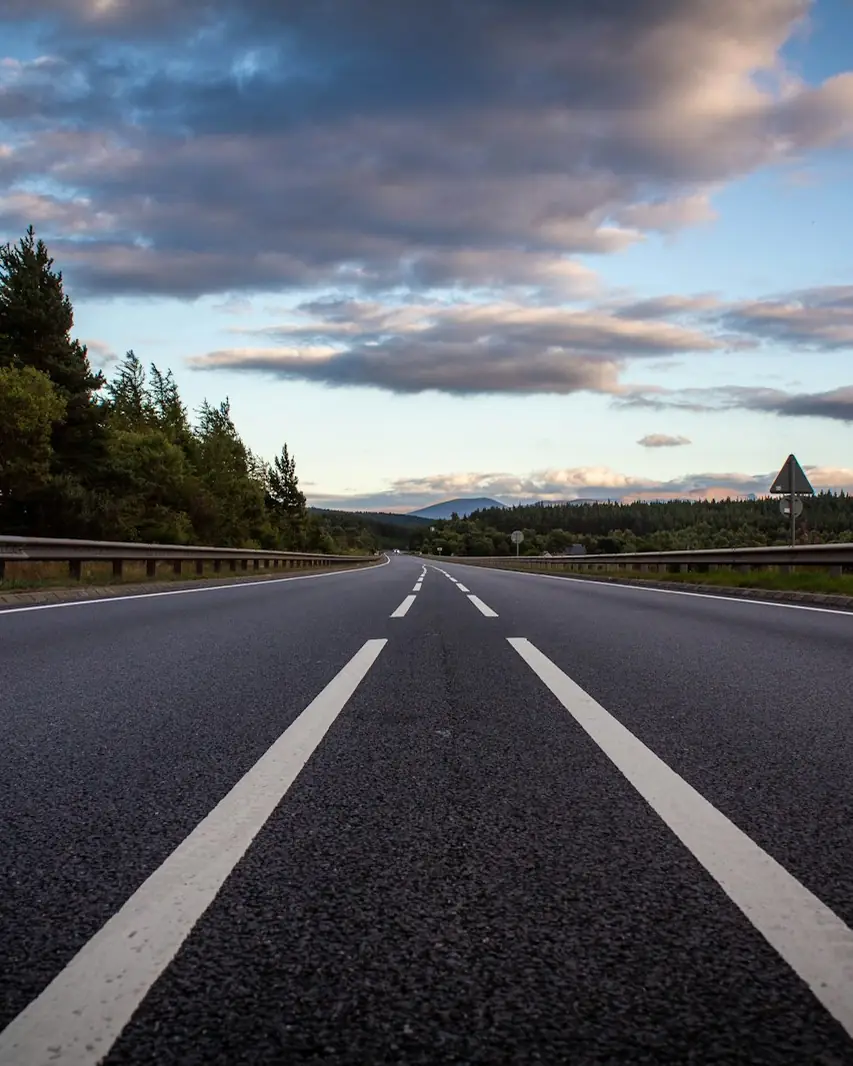 Open highway lined with trees under evening clouds