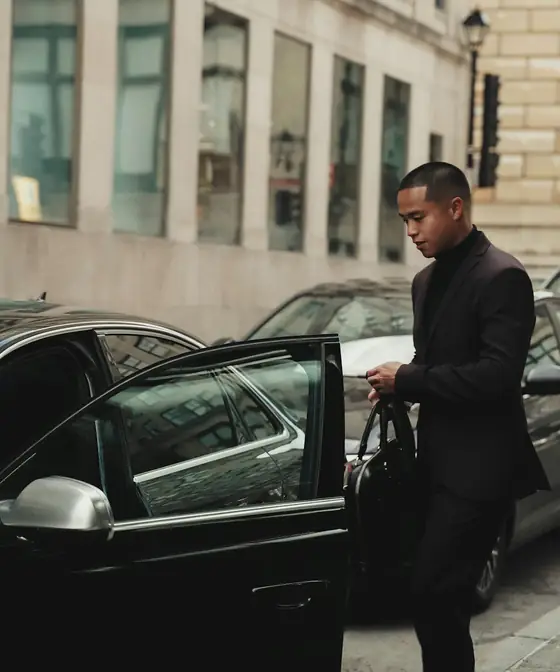 Chauffeur in a dark suit at the door of a black car